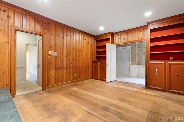 interior space with wood walls, light hardwood / wood-style floors, and ornamental molding