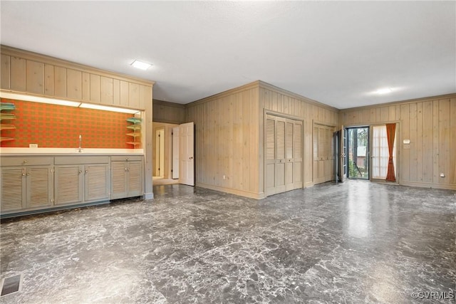 interior space with wood walls, ornamental molding, and light brown cabinetry