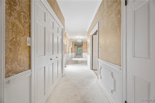 hallway featuring light carpet, crown molding, and a notable chandelier