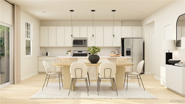 kitchen with stainless steel appliances, a kitchen island with sink, pendant lighting, light hardwood / wood-style flooring, and white cabinets