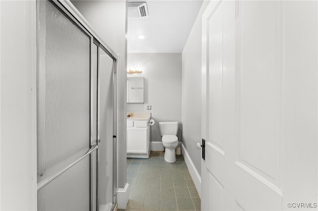 bathroom featuring vanity, toilet, and a shower with door