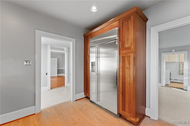 hallway featuring independent washer and dryer, a baseboard heating unit, and light wood-type flooring