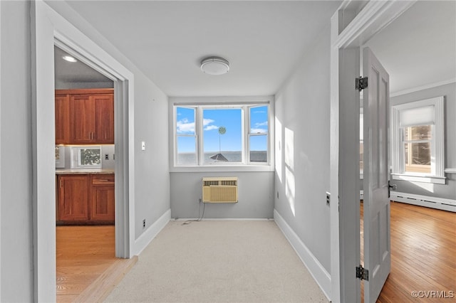 hall featuring a wall unit AC, crown molding, light hardwood / wood-style flooring, and a baseboard heating unit