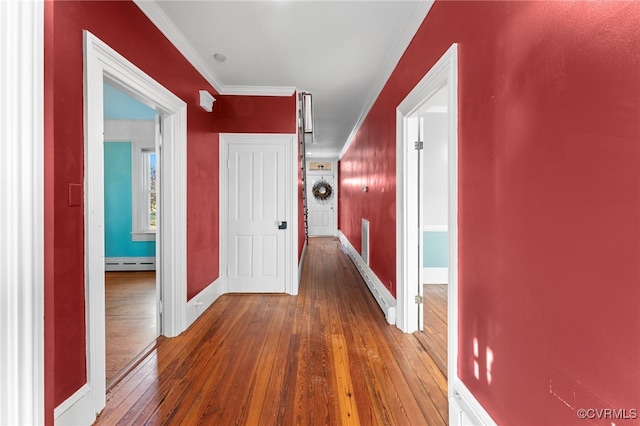 corridor with dark hardwood / wood-style flooring, crown molding, and a baseboard heating unit