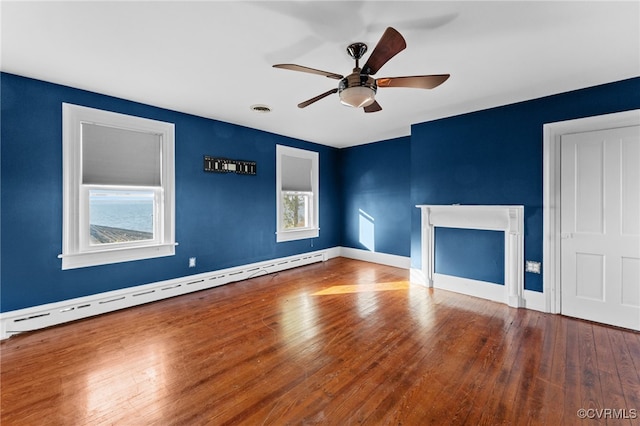 unfurnished living room with baseboard heating, plenty of natural light, and wood-type flooring