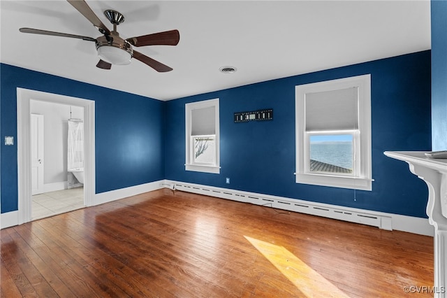 interior space featuring wood-type flooring, connected bathroom, baseboard heating, and ceiling fan