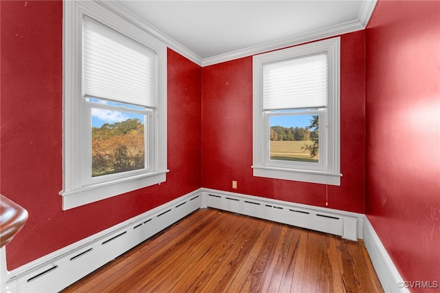 empty room with a wealth of natural light, crown molding, and wood-type flooring