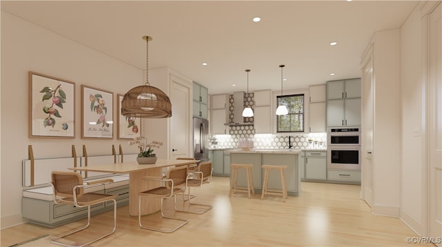 kitchen featuring a breakfast bar, a center island, hanging light fixtures, light hardwood / wood-style floors, and stainless steel appliances