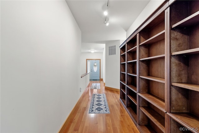 hallway featuring rail lighting and light hardwood / wood-style flooring