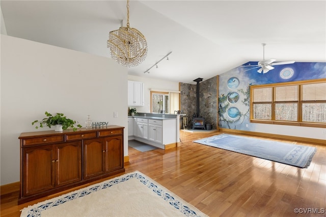 kitchen with white cabinetry, a wood stove, a wealth of natural light, and light hardwood / wood-style flooring