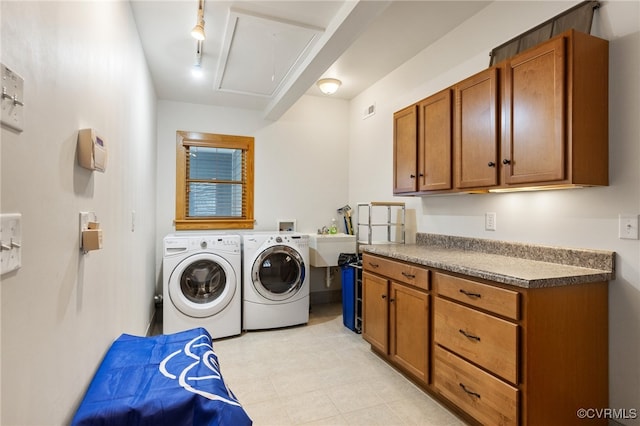 clothes washing area with washer and dryer, cabinets, and sink