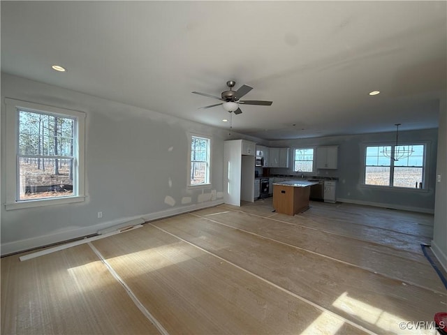 kitchen featuring white cabinets, a kitchen island, open floor plan, hanging light fixtures, and light countertops