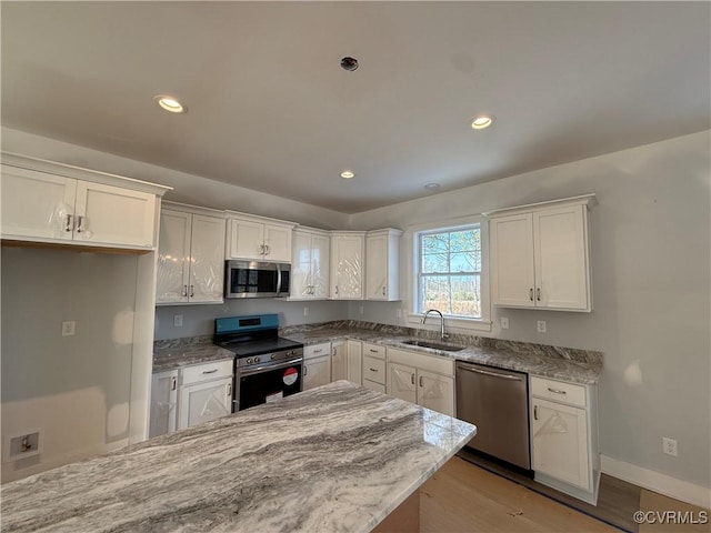 kitchen featuring light stone counters, a sink, white cabinets, appliances with stainless steel finishes, and light wood-type flooring