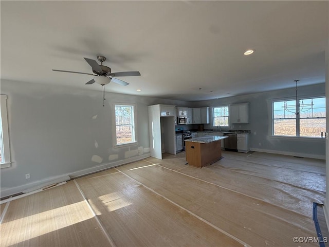 kitchen with stainless steel appliances, a center island, open floor plan, and white cabinetry