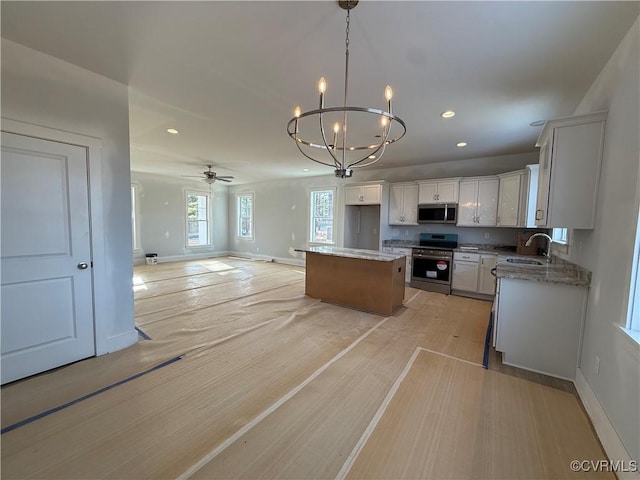 kitchen with a center island, stainless steel appliances, open floor plan, white cabinetry, and a sink