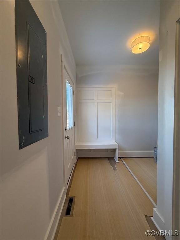 hall featuring baseboards, electric panel, visible vents, and light wood finished floors