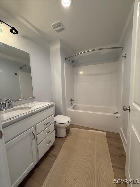 full bath featuring bathing tub / shower combination, visible vents, wood finished floors, and vanity