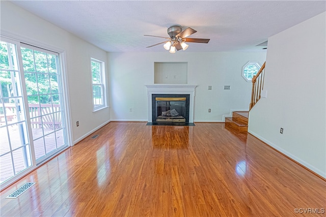 unfurnished living room with ceiling fan, wood-type flooring, and a textured ceiling