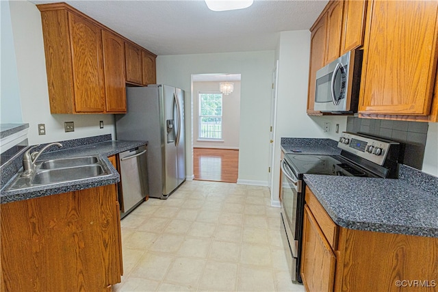 kitchen with decorative backsplash, appliances with stainless steel finishes, a textured ceiling, sink, and a chandelier