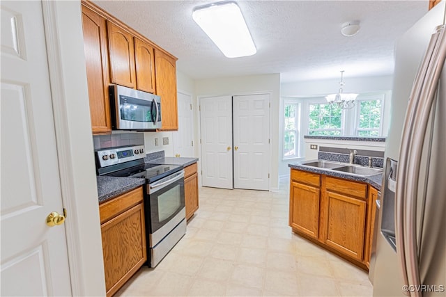 kitchen featuring backsplash, an inviting chandelier, sink, appliances with stainless steel finishes, and decorative light fixtures