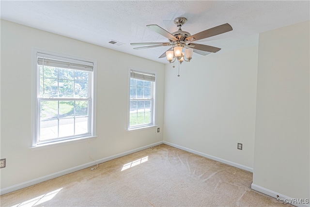 spare room featuring ceiling fan, light colored carpet, and a textured ceiling