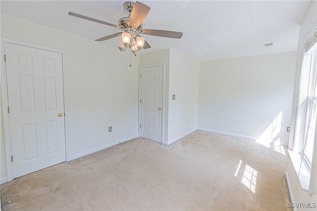 spare room featuring light colored carpet and ceiling fan