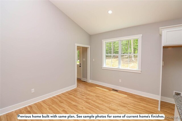 spare room featuring hardwood / wood-style flooring and vaulted ceiling