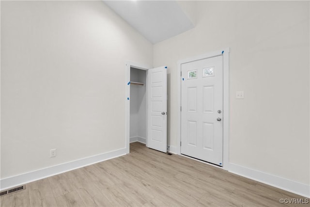 unfurnished bedroom with lofted ceiling, visible vents, baseboards, and light wood finished floors