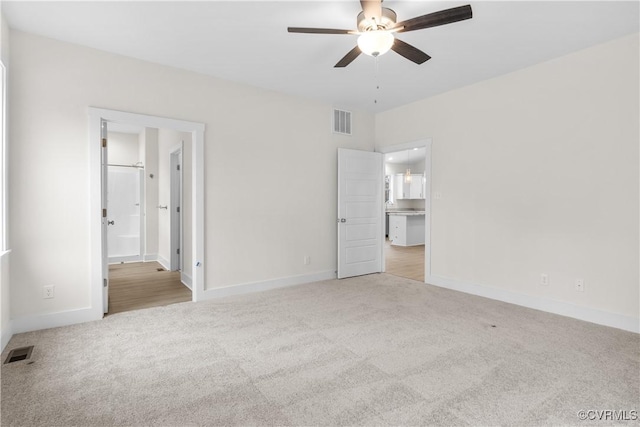 unfurnished bedroom featuring ensuite bath, carpet, and visible vents