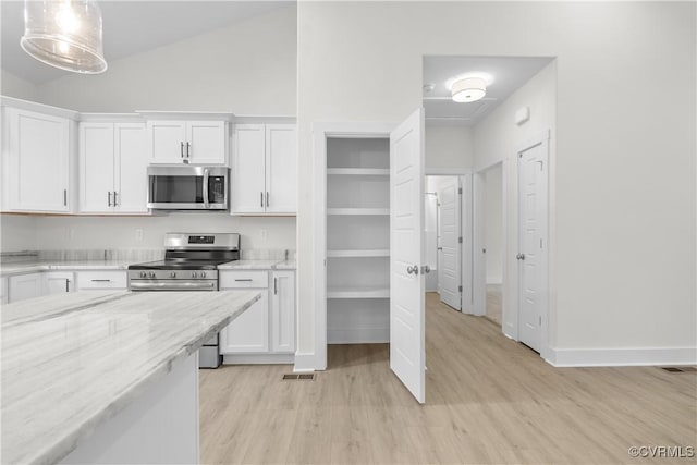 kitchen with light stone counters, white cabinetry, appliances with stainless steel finishes, light wood finished floors, and lofted ceiling