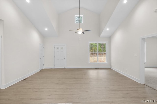 unfurnished living room featuring a wealth of natural light, light wood-style flooring, and high vaulted ceiling