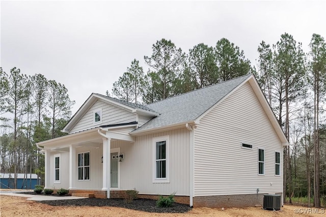 view of front of property featuring a porch, central AC unit, and a shingled roof