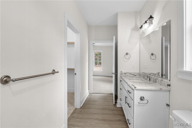 bathroom with baseboards, toilet, wood finished floors, and vanity