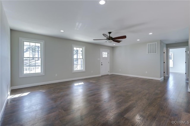 empty room featuring a wealth of natural light, dark hardwood / wood-style flooring, and ceiling fan