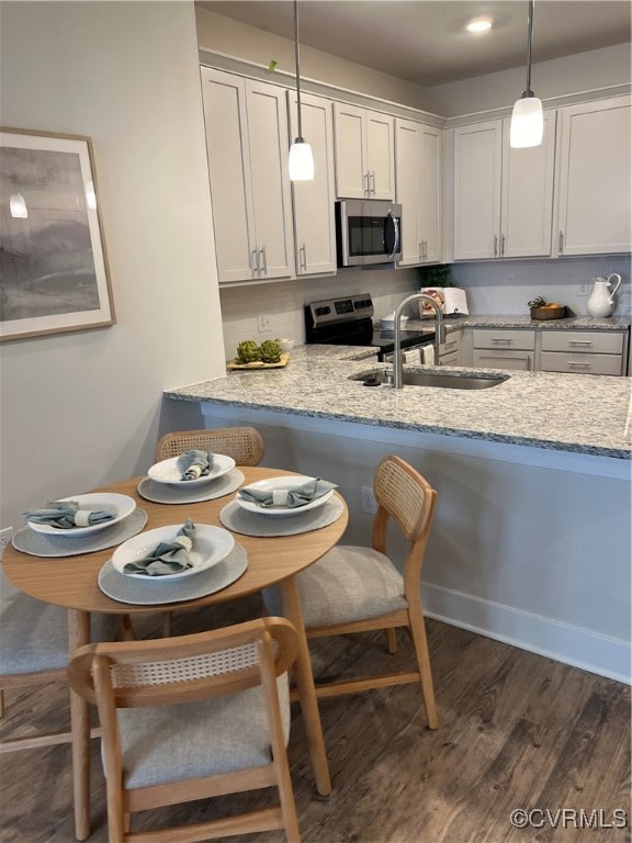 kitchen featuring light stone countertops, stainless steel appliances, and decorative light fixtures