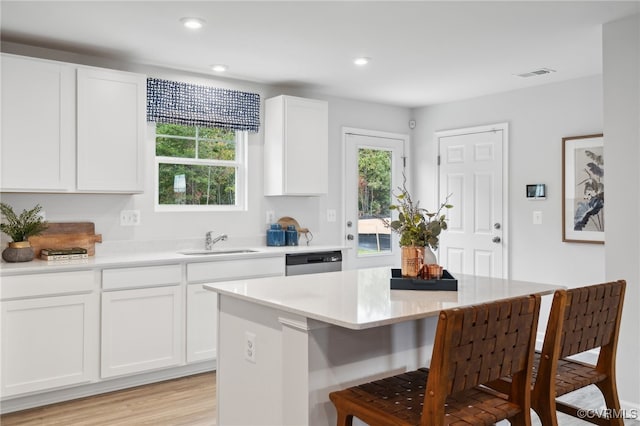 kitchen featuring sink, dishwasher, a center island, light hardwood / wood-style floors, and white cabinetry