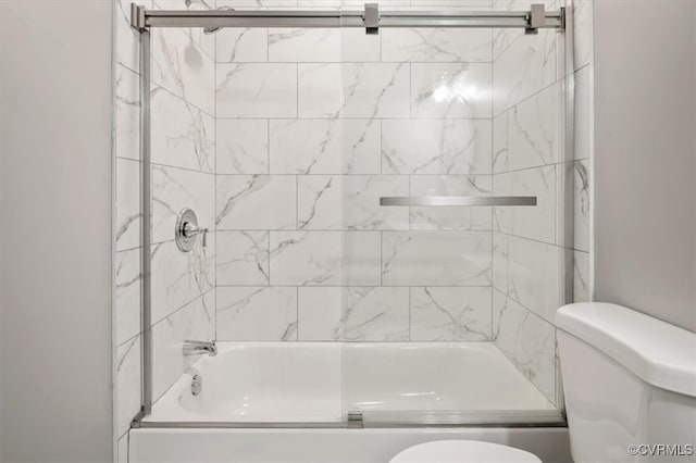 bathroom featuring toilet and bath / shower combo with glass door