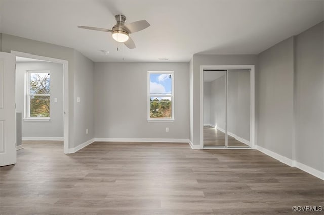 unfurnished bedroom with ceiling fan, light hardwood / wood-style floors, and multiple windows