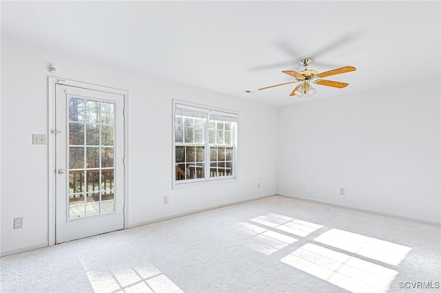 empty room featuring a wealth of natural light, ceiling fan, and light carpet