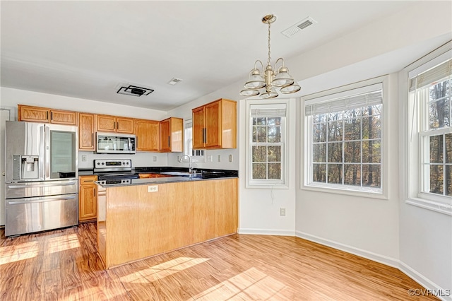 kitchen featuring kitchen peninsula, stainless steel appliances, sink, an inviting chandelier, and light hardwood / wood-style flooring