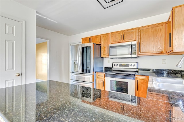 kitchen with sink, dark stone counters, and appliances with stainless steel finishes