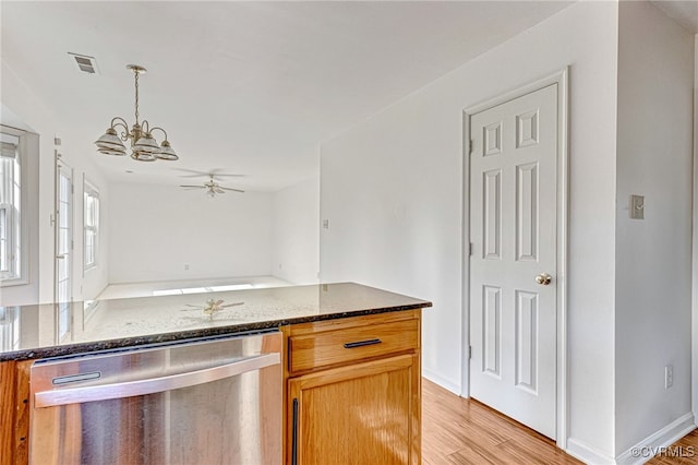 kitchen featuring ceiling fan with notable chandelier, light wood-type flooring, stainless steel dishwasher, and dark stone counters