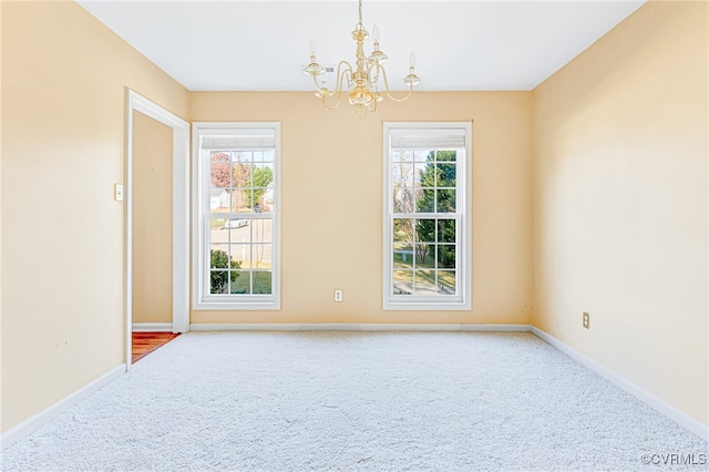 carpeted spare room with a chandelier and a wealth of natural light