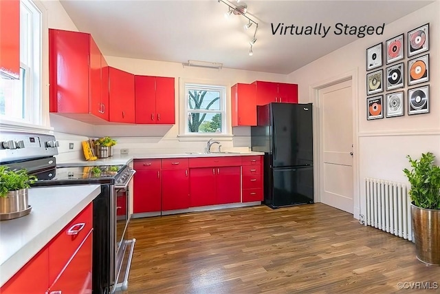 kitchen with stainless steel electric range, dark wood-type flooring, radiator, black refrigerator, and sink