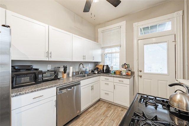 kitchen featuring appliances with stainless steel finishes, ceiling fan, sink, white cabinets, and light hardwood / wood-style floors