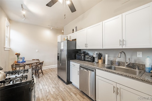 kitchen with appliances with stainless steel finishes, light wood-type flooring, rail lighting, sink, and white cabinets