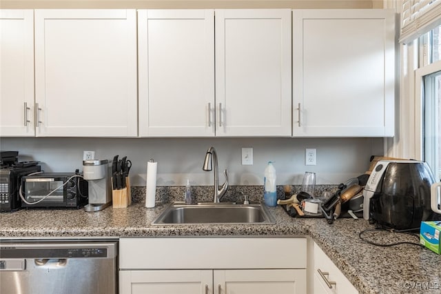 kitchen featuring white cabinets, dishwasher, light stone countertops, and sink