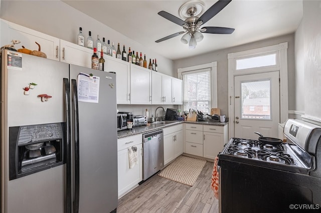 kitchen with sink, white cabinets, stainless steel appliances, and light wood-type flooring