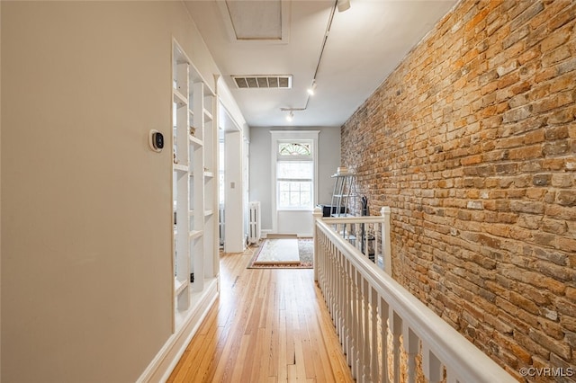 hall featuring light hardwood / wood-style flooring and brick wall