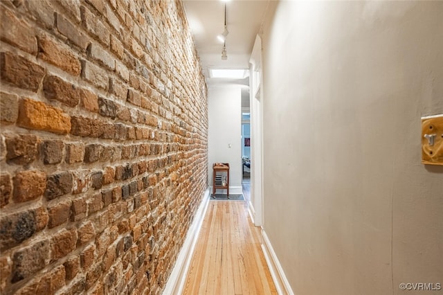 hall with wood-type flooring and brick wall